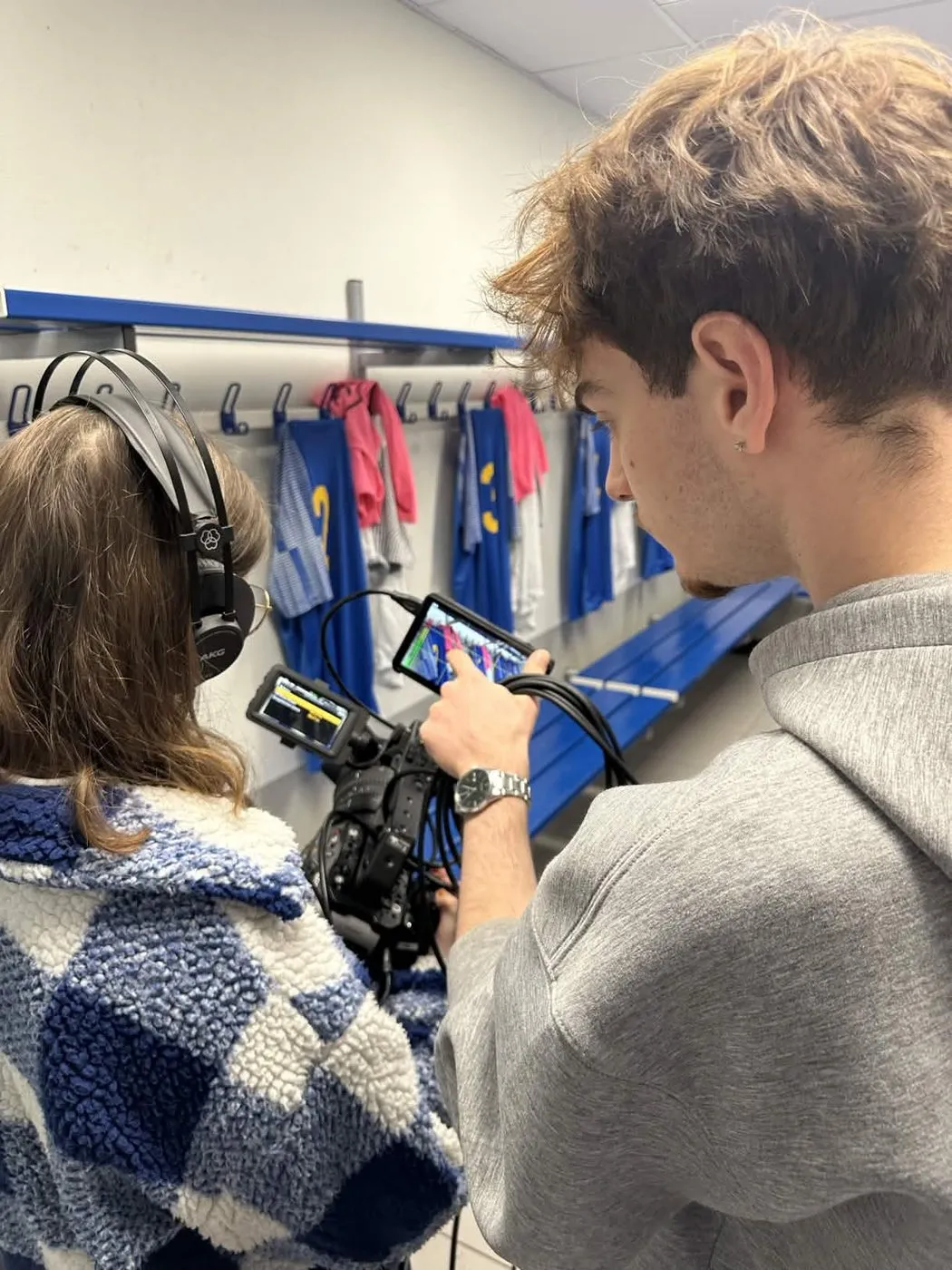 Prise de vue casque sur les oreilles dans les vestiaires du club, maillots accrochés au fond