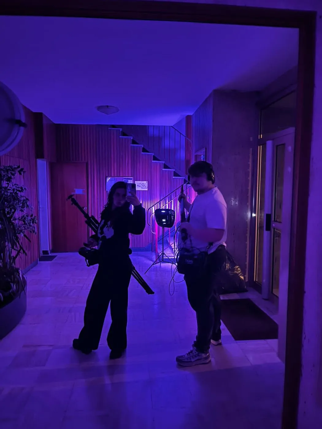 Tournage dans un couloir éclairé en violet, perche et caméra à l'épaule