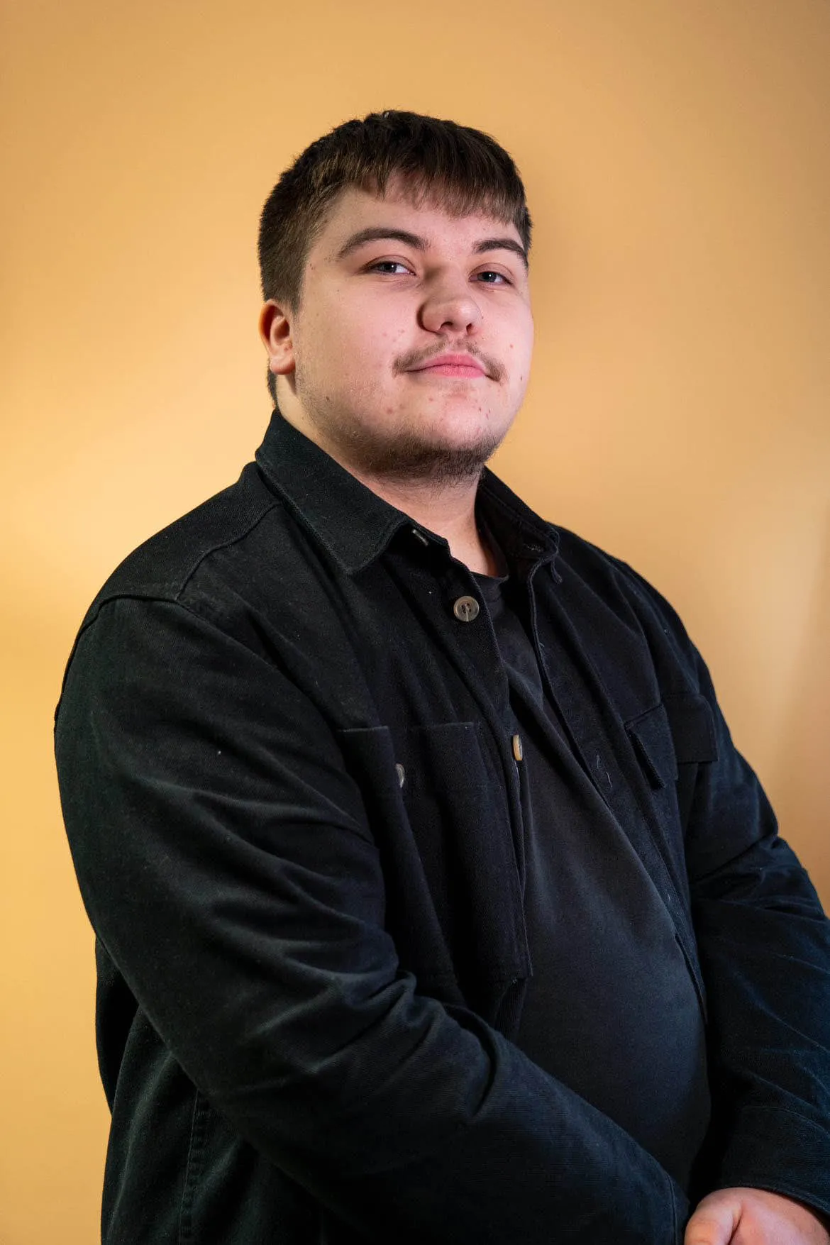 Clément Dubois en portrait studio sur fond orange